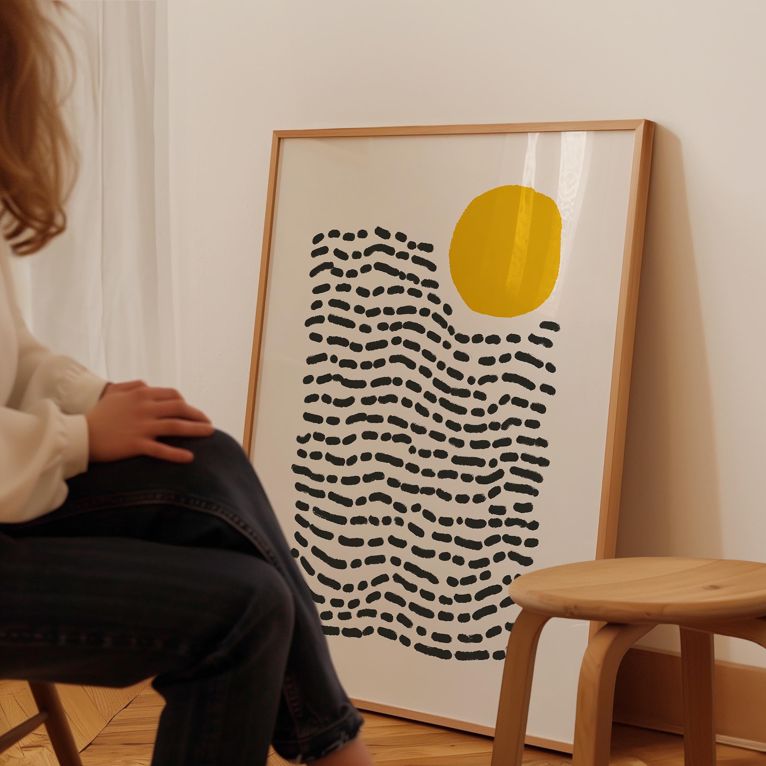 A person is sitting in a chair in front of a large abstract art print on a wall.