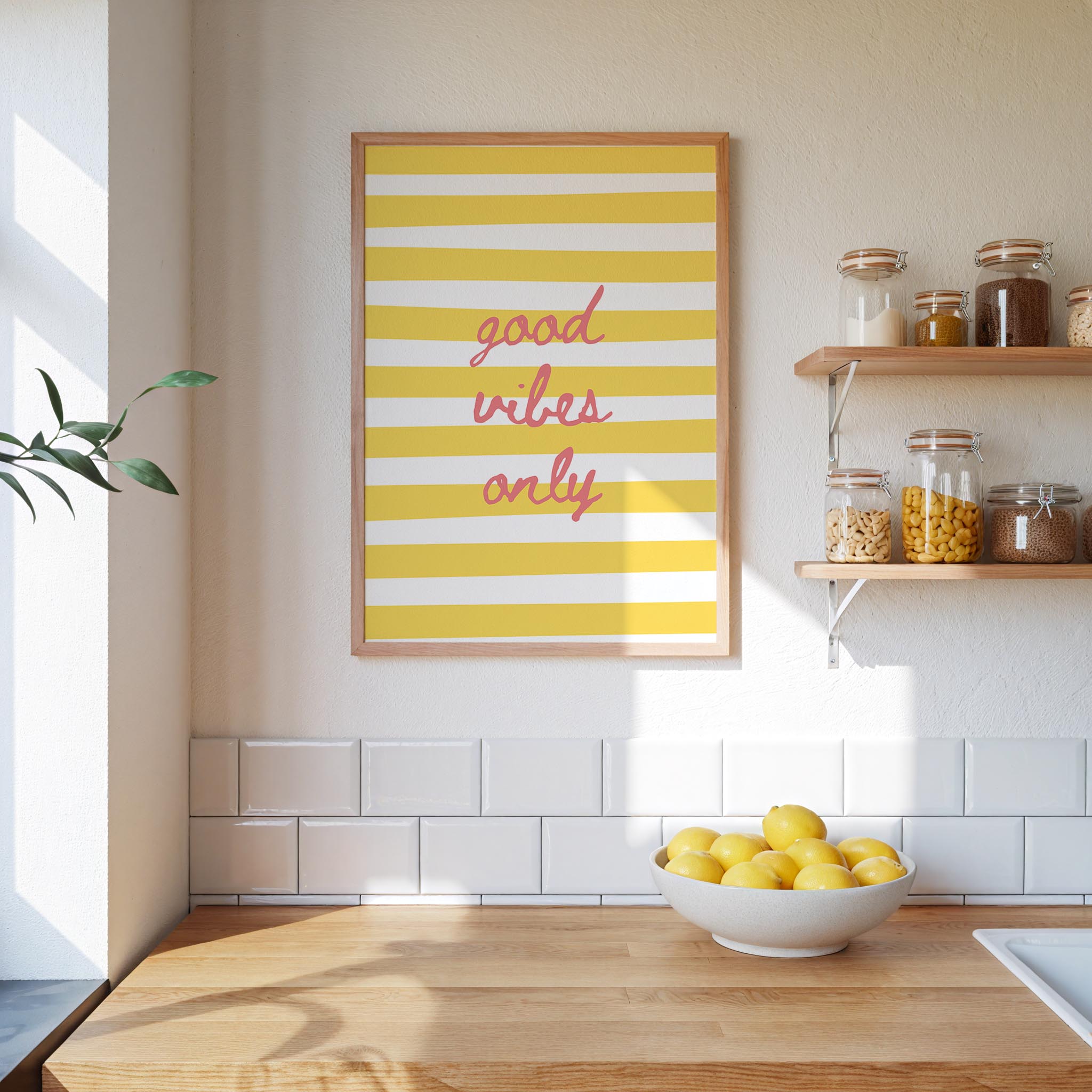 a kitchen counter with a bowl of lemons, a framed poster with the text "good vibes only", and shelves displaying various jars and containers.