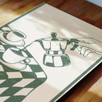 A close-up of a printed image depicting a coffee maker and a cup of coffee on a checkered tablecloth.