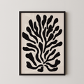 a framed abstract art piece with a black and white design of stylized shapes resembling a plant or tree.