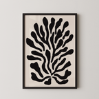 a framed abstract art piece with a black and white design of stylized shapes resembling a plant or tree.