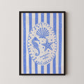 The image is a framed print featuring a blue and white design with a central illustration of a seahorse, starfish, and seashell, surrounded by blue and white striped patterns.