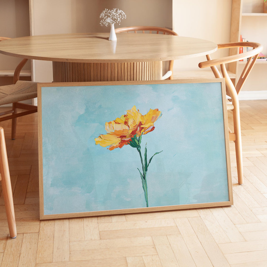 a large framed painting of a yellow flower on a wooden table.