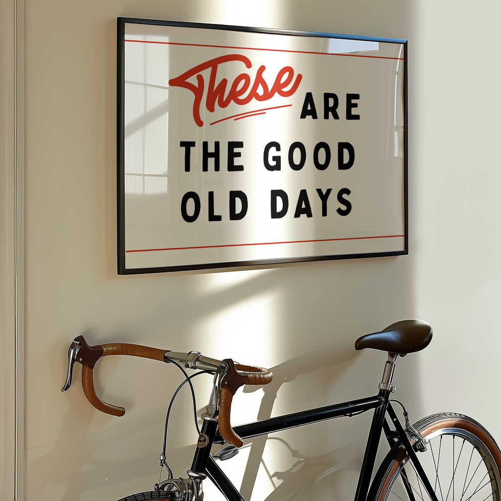 a framed sign with the text "These are the good old days" hanging on a wall next to a bicycle.