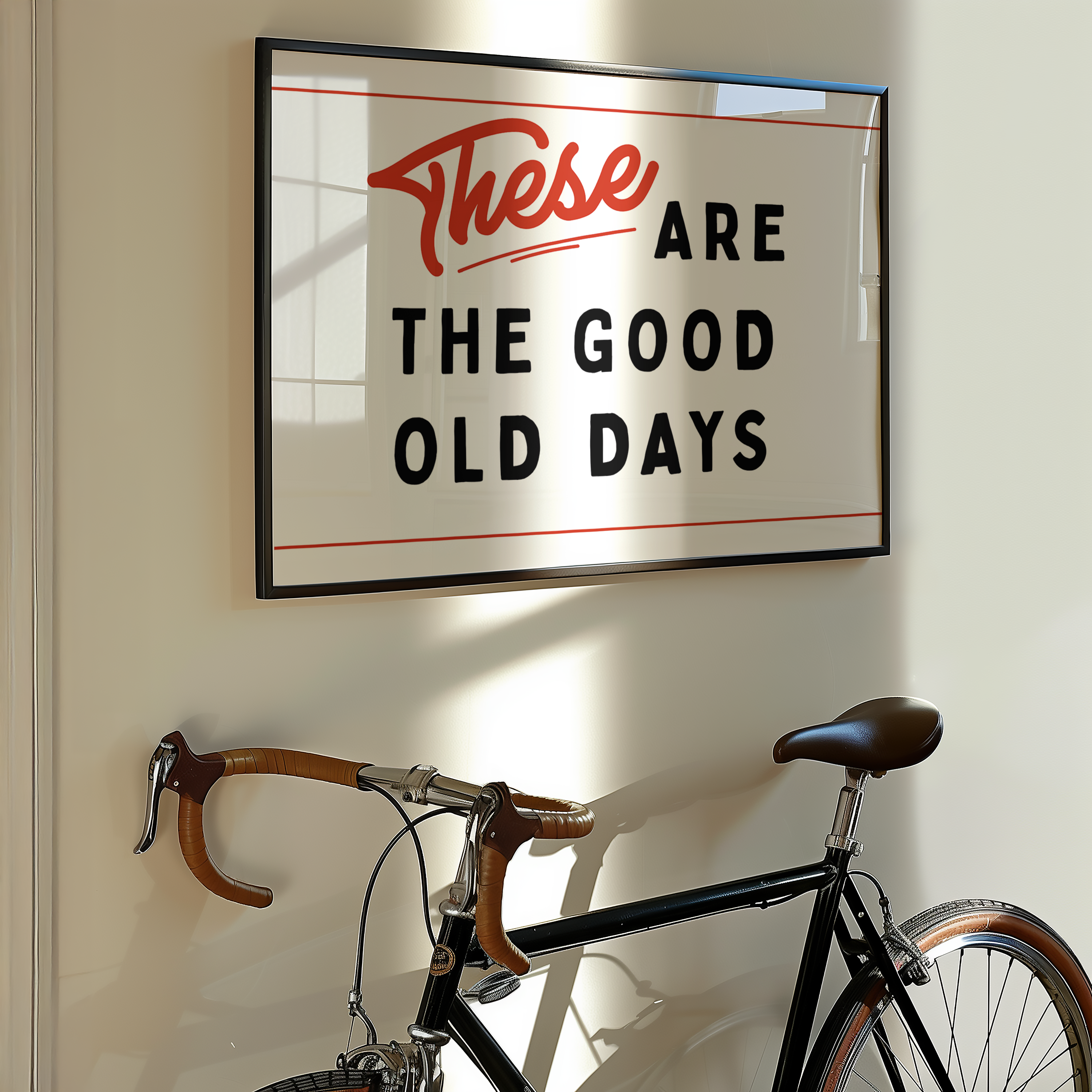 a framed sign with the text "These are the good old days" hanging on a wall next to a bicycle.