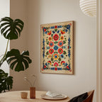 a wooden table with a vase of flowers, a plate, and a cup, set against a wall with a framed picture of a colorful floral design hanging above it.
