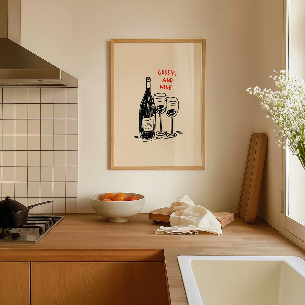 a kitchen counter with a framed drawing of a wine bottle and two wine glasses, along with a bowl of fruit and a vase of flowers.