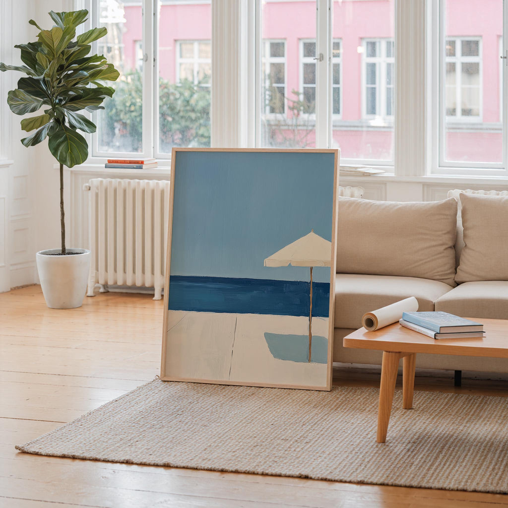 a living room with a large painting of a beach scene on the floor, a sofa, a coffee table, and a potted plant.