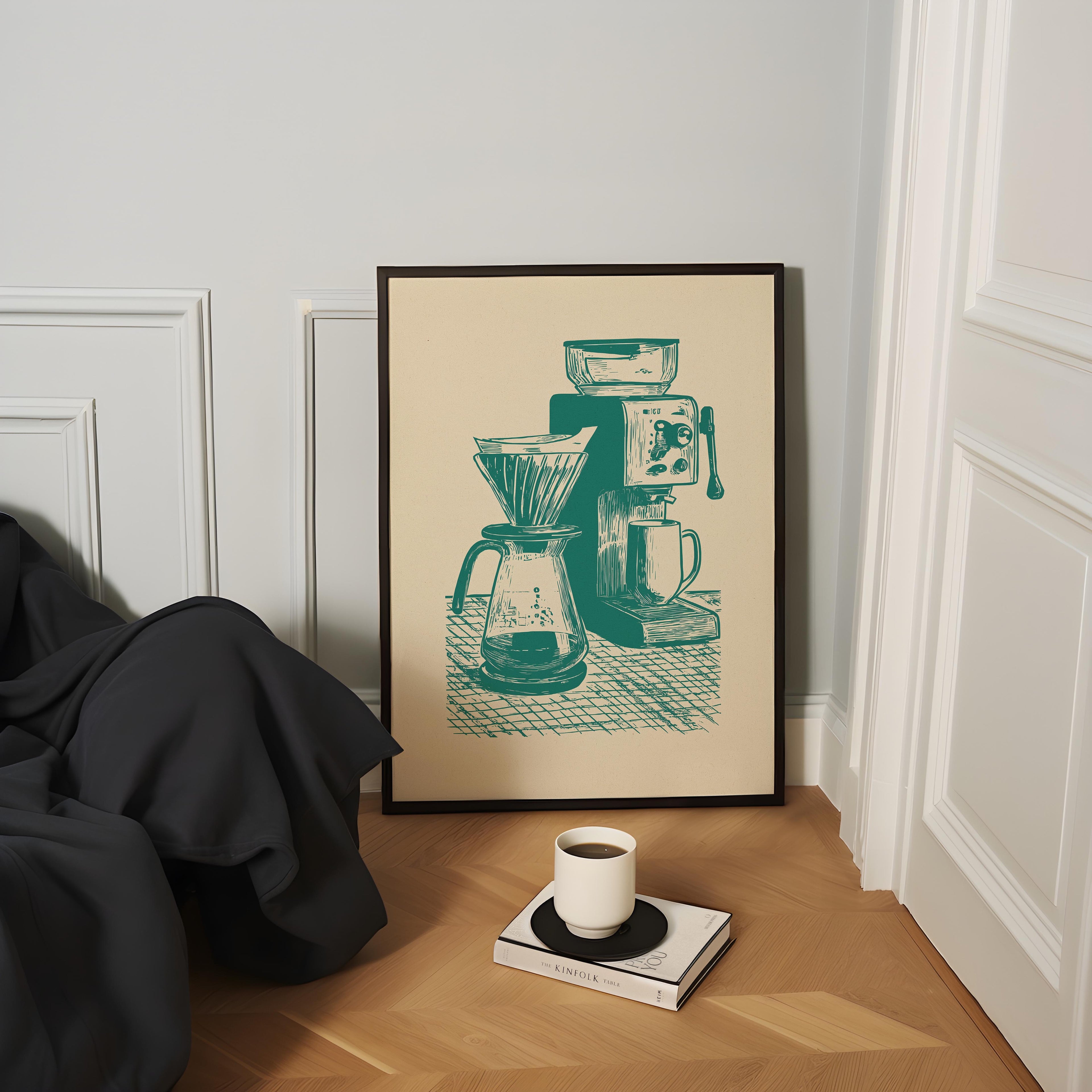 a framed illustration of a coffee maker and a coffee cup on a wooden floor, with a book and a cup of coffee placed nearby.