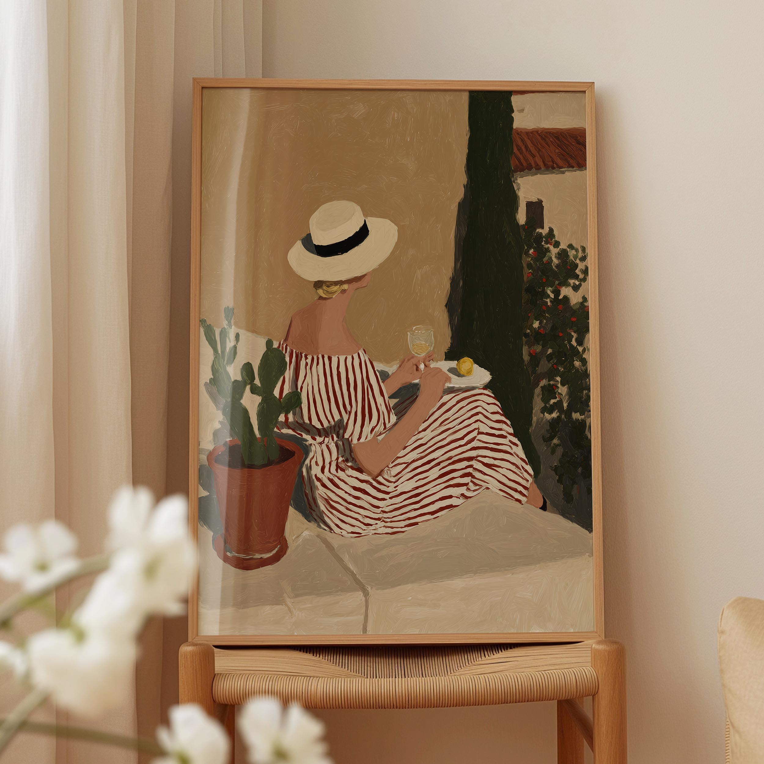 A framed painting depicting a woman in a striped dress sitting on a bench, holding a glass of wine and surrounded by potted plants.