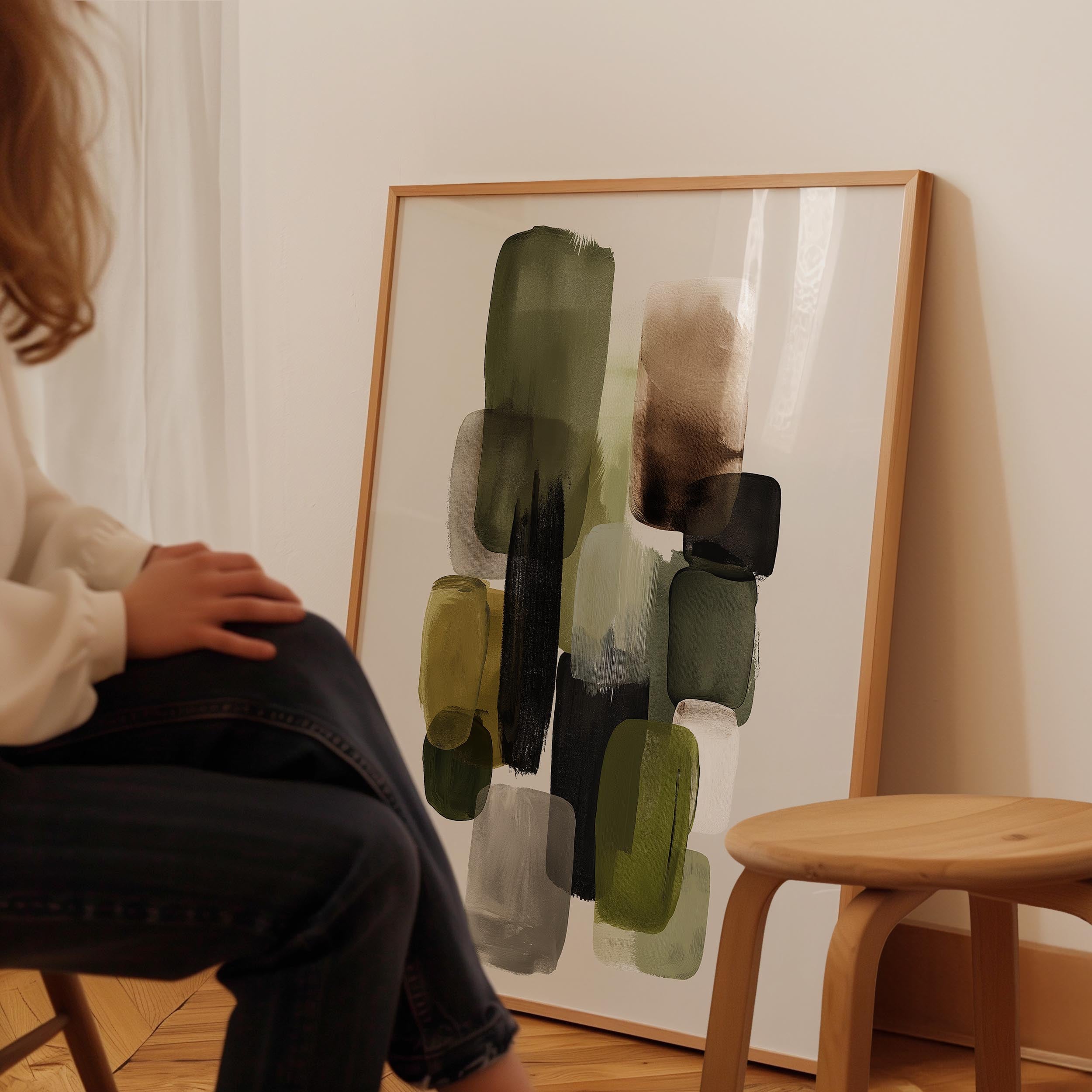 A person is sitting in a chair in front of a large abstract painting on the wall.