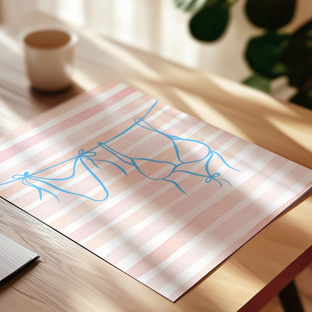a pink and white striped paper with a blue drawing of a ribbon on it, placed on a wooden surface.