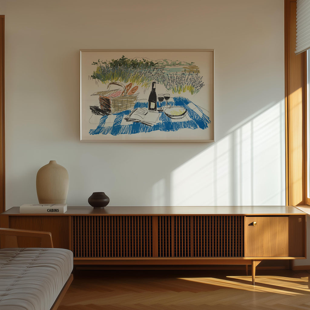 a wooden cabinet with a vase and a book on top, and a framed painting of a picnic scene hanging on the wall above it.