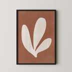 a framed abstract art piece with a brown background and a white leaf-like shape.