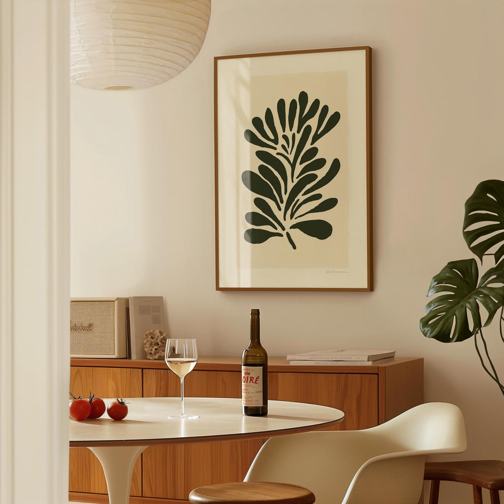 a dining room with a table, a wine bottle, a wine glass, and a framed plant on the wall.